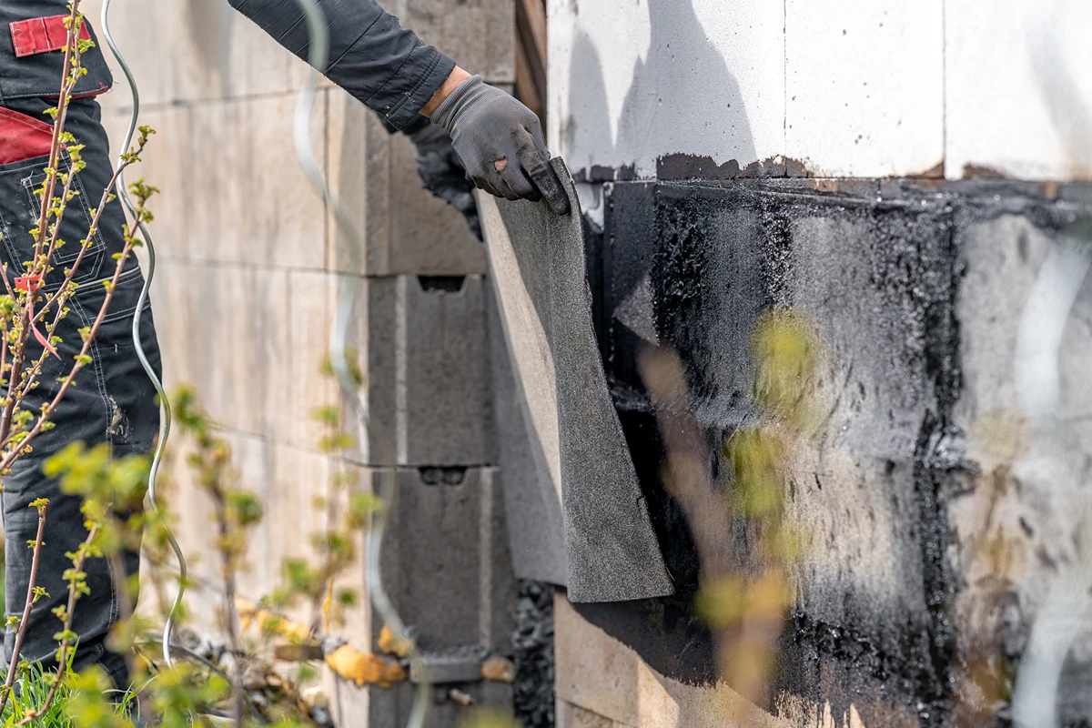 Builder applying external waterproofing to facade, one of the main concerns of AS4654
